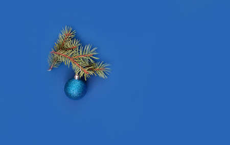 Festive New Year's content with a place for text, on a blue background a sprig of pine, a ball, a...