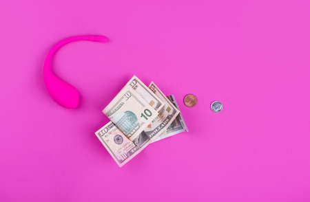 A female pink vibrator with money rests on a pink background . Intimate themeの写真素材