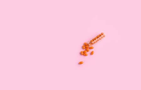 Orange tablets in a glass flask. Vitamins, health. Composition on a pink background.の写真素材