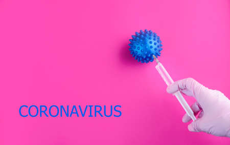The hand in the gloves holds a syringe and injects the virus. Content for coronavirus on a pink...