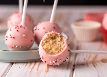 The pastry chef decorates cake pops with satin ribbons. Desserts with pink cream. Tasty foodの写真素材
