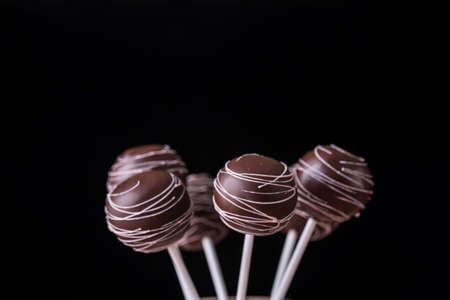 Cake pops in chocolate cream in the form of a bouquet stand in jars with sugar on a wooden background. Tasty foodの写真素材