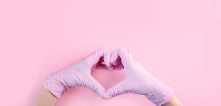 Hands in medical gloves are pink in the shape of a heart on a pink background with a place for text.