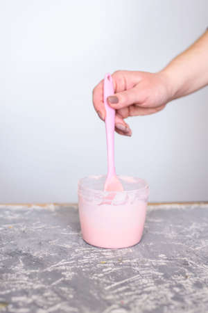 Dairy strawberry cream for desserts. Liquid chocolate cream with a silicone spatula in the hands of a pastry chef.の写真素材