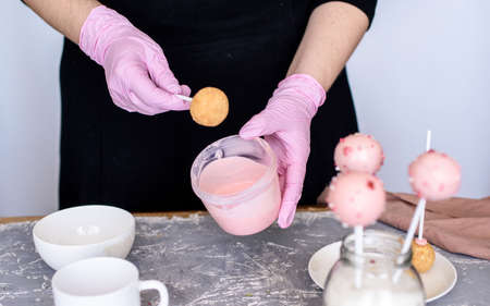 The pastry chef makes dessert on a stick. Cake pops. Chocolate cream for dessert, creation process. Sprinkle for dessert.の写真素材