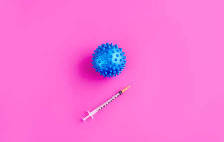The hand in the gloves holds a syringe and injects the virus. Content for coronavirus on a pink background. COVID-19の写真素材