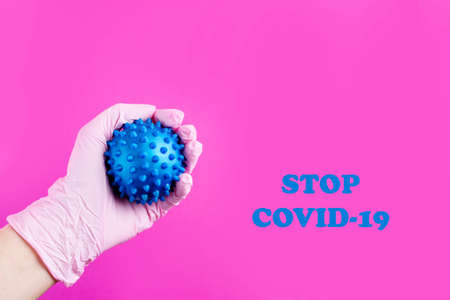 The hand in the gloves holds a syringe and injects the virus. Content for coronavirus on a pink background.の写真素材