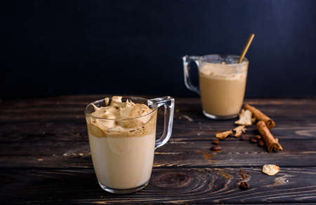 Delicious and fragrant dalgona coffee in glass cups, cinnamon sticks, dried mushrooms, a spoon of...