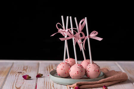 Cake pops in pink cream lie on a beautiful plate. Delicious close-up dessert.の写真素材