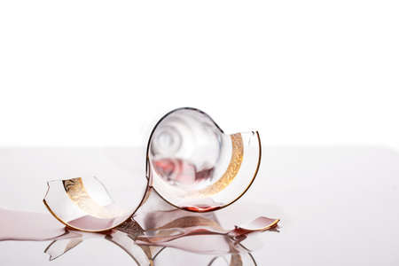 A broken glass with droplets of wine lies on a light background. Broken glass pack on the skylight.