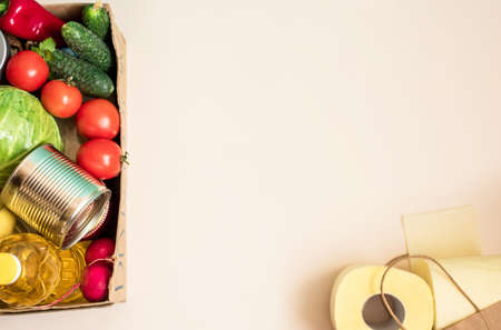 A box of fresh produce, vegetables, butter, stew, toilet paper for donation. View from above, place for inscription.の写真素材
