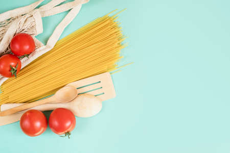 Spaghetti on a light background with tomatoes, wood spoon. Eco bag. Foodの写真素材