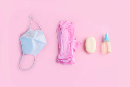 Blue face mask, pink gloves, and hand aptic lie on a pink background. Protection from the virusの写真素材