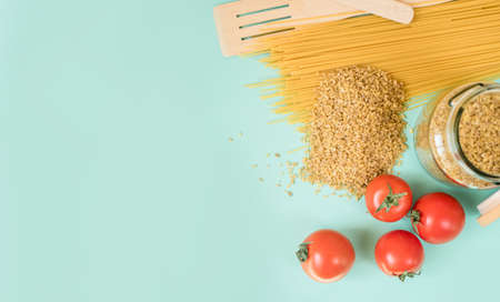 Fresh produce on a light background. Spaghetti, tomato, bulgur, stew, pepper, eco bag. View from above, place for text.の写真素材