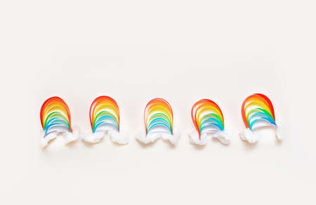 A small rainbow of colored paper with clouds of snow, creativity with their hands on a light background. DIYの写真素材