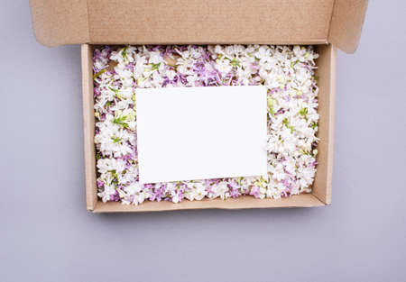 The eco box is filled with lilac flowers of different colors, and a white postcard for...