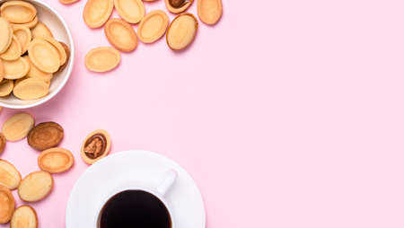 Homemade Russian nuts with condensed milk on a light pink background, wafer napkin. Cut nuts with condensed milk. Bitten goodies for coffee. Condensed Nutsの写真素材