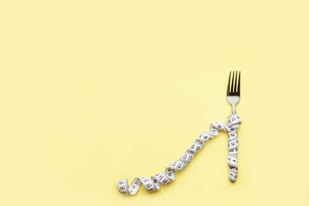 The fork lies on a colored background enquired by an inch. Proper nutrition, diet, place for text,...