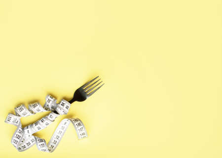 The fork lies on a colored background enquired by an inch. Proper nutrition, diet, place for text,...