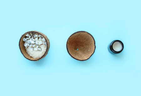Coconut cut into pieces, coconut shavings, green leaves, shea butter on a blue background. A place...