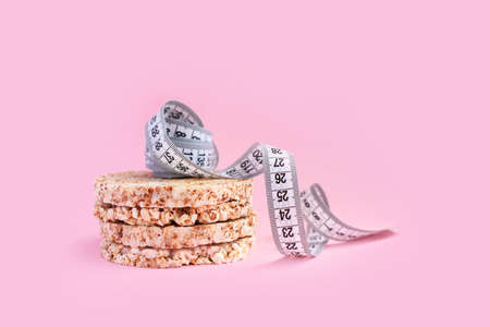 Four rice loaves, lie on a pink background on top of a centimeter. Proper nutrition, healthy food. Place for textの写真素材