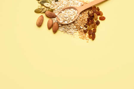Two spoons of different sizes are filled with oatmeal and golden flax, raisins, almonds, pumpkin seeds. Healthy breakfast, proper nutrition, diet. A place for text.の写真素材