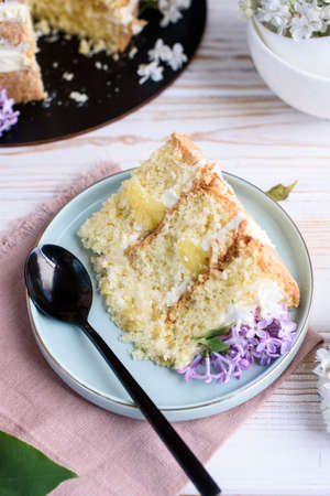 Biscuit cake with cream, impregnated with coconut and pineapple, decorated with lilac flowers. Delicious dessert, food photo.の写真素材