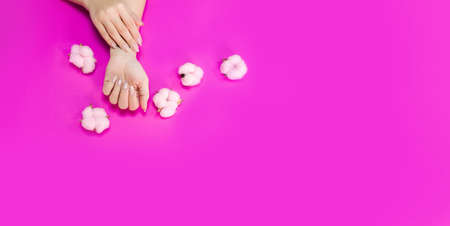 Beautiful women's manicure in delicate tones, on a bright background with gently pink cotton. Place for the inscription. View from above.の写真素材