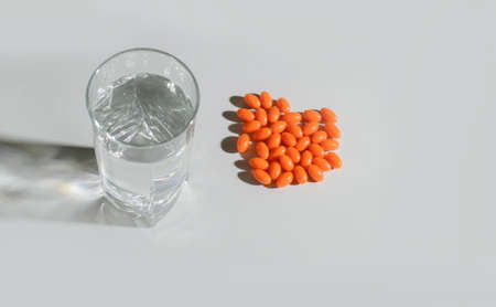 A glass of clean water with natural vitamins, with shadows on a light background. View from above....
