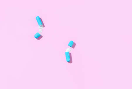 Two blue capsules of white powder medication. View from above