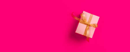 Banner with pink background with a beautiful box for a gift. A place for text. View from above. Flat...