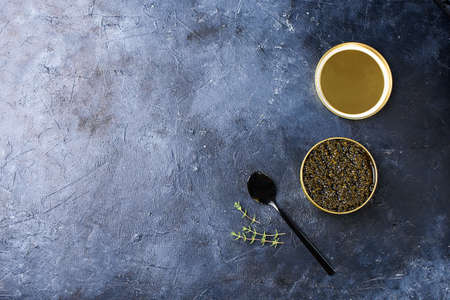 Black sturgeon caviar with a black spoon and a dark background. Seafood, healthy food.