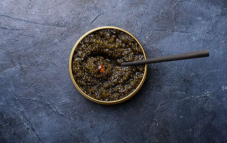 Black sturgeon caviar with a black spoon and a dark background. Seafood, healthy food.