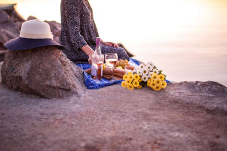 A girl with flowers by the sea at dawn at a picnic. Romantic morning. Early morning in summer.の写真素材