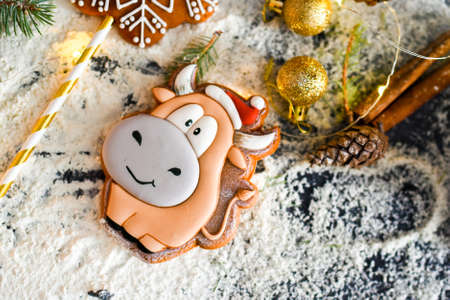Delicious fragrant gingerbread in the form of a bull, a symbol of the new year. Cinnamon sticks, Christmas golden balls for the Christmas tree, conesの写真素材