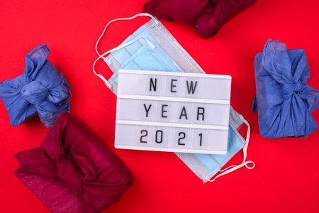 Light box with the inscription New Year, face mask from viruses, watch on a red background. New year 2021 awareness. Coronavirus Pandemic Into 2021の写真素材