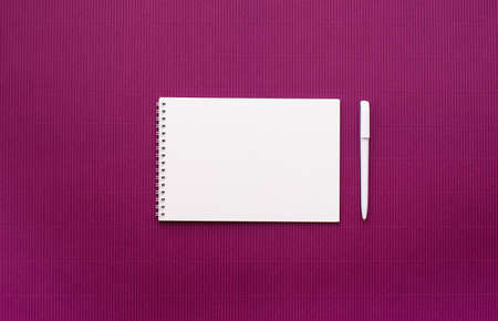 Notebook with white sheets on a spring with empty pages, white pen, light lilac background. View from above, place for text.の写真素材