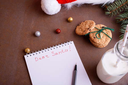 Delicious cookies with chocolate on a white plate, milk, santa hat, muck up for text. Letter and cookies for Santa.の写真素材