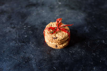 Delicious shortbread cookies with pieces of chocolate, with a beautiful ribbon on a dark background....