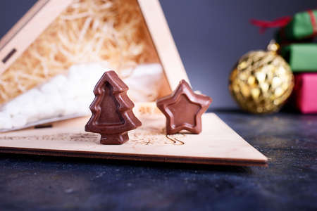 A wooden box gift with a marshmallows for coffee and spoons with chocolates in the form of a star Christmas tree. New Years content.の写真素材