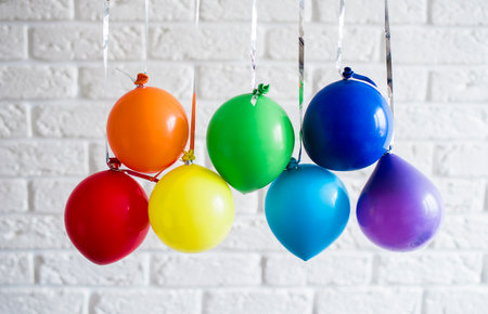Small inflatable balls of rainbow colors hang on a ribbon. Holiday content. Art conceptの写真素材