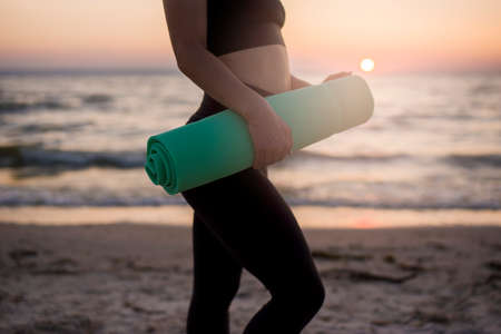 Playing sports on the shore of the sea at dawn. The girl does yoga on the sand by the sea. Sports...