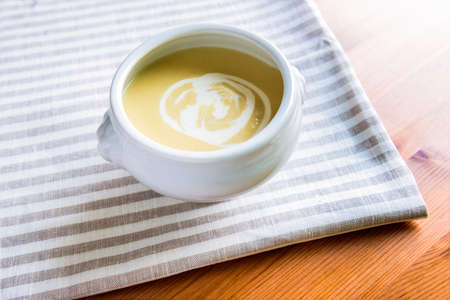 Bowl of asparagus cream soup is on the striped napkin. Two heads of asparagus are in the bowl. View from aboveの写真素材