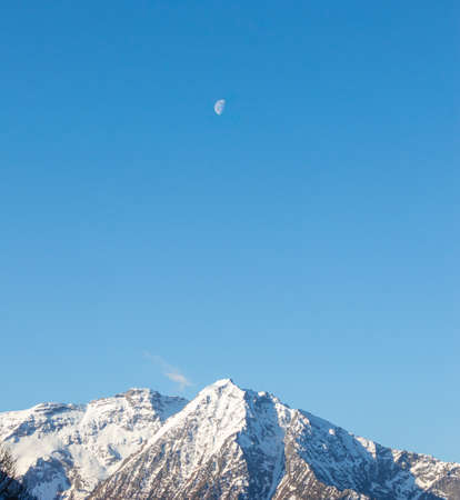 Minimal mountain peak landscape with the moon in the blu clear skyの写真素材