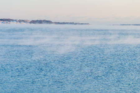 Minimal view of the sea from Helsinki coastline. The weather is so cold that the water freezes and crates a light mist on its surfaceの写真素材