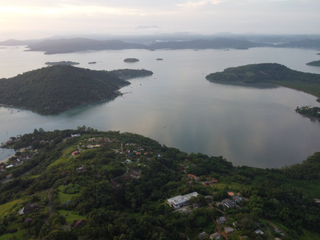 Sunset drone video over Paraty, Brazil, reveals lush Atlantic Forest, golden skies, and small islands scattered along the glowing coastline.の写真素材