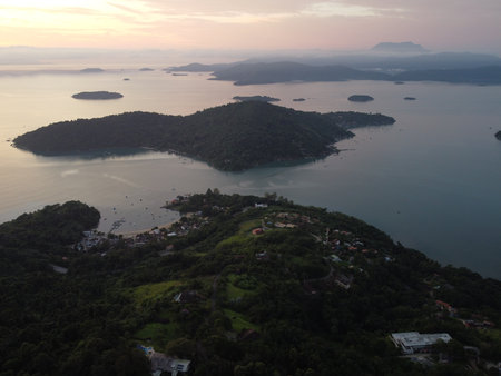 Sunset drone video over Paraty, Brazil, reveals lush Atlantic Forest, golden skies, and small islands scattered along the glowing coastline.の写真素材