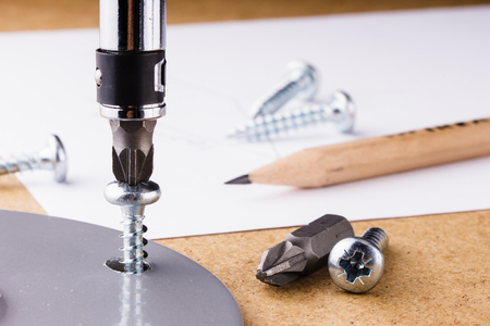 The screwing of the screw with a screwdriver. Screw the metal part to the wooden surface with a screwdriver.の写真素材