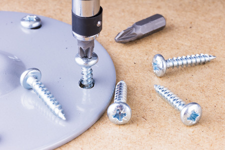 The screwing of the screw with a screwdriver. Screw the metal part to the wooden surface with a...
