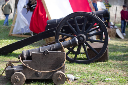 Two medieval cannons are displayed on a grass field during a historical reenactment, showcasing the weaponry of the pastの写真素材